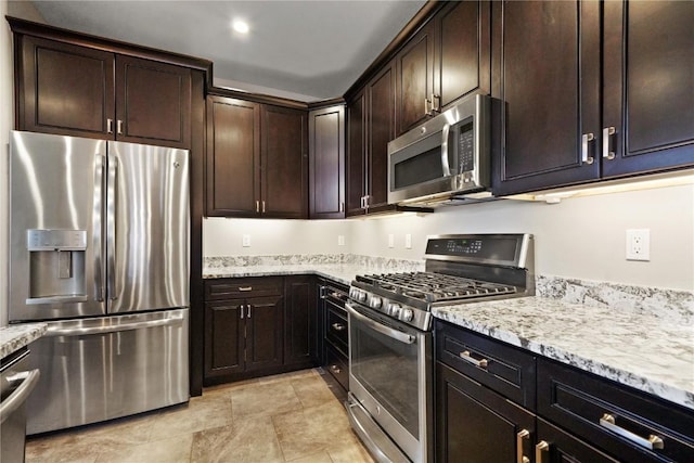 kitchen with dark brown cabinets, appliances with stainless steel finishes, and light stone countertops