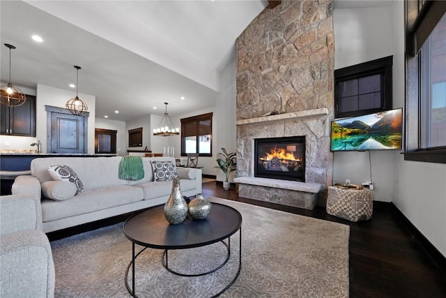 living area featuring baseboards, a stone fireplace, recessed lighting, an inviting chandelier, and wood finished floors