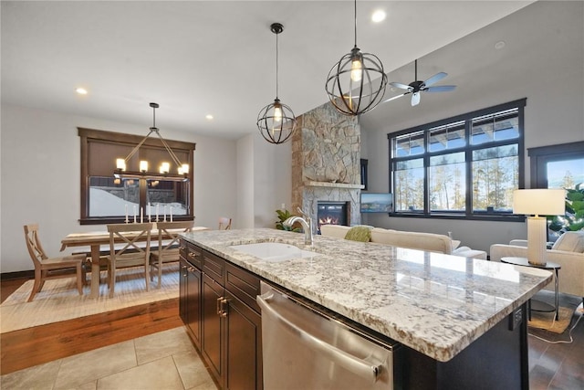 kitchen with stainless steel dishwasher, a fireplace, open floor plan, and a sink