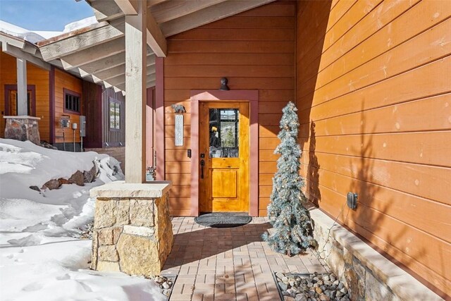 snow covered property entrance with a porch