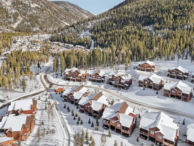 snowy aerial view featuring a forest view, a mountain view, and a residential view