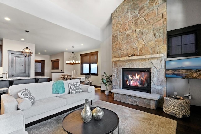 living area with recessed lighting, a chandelier, a stone fireplace, and wood finished floors