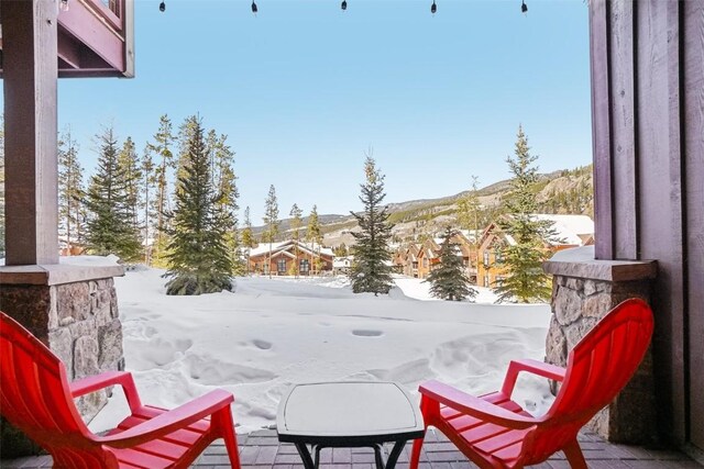 snow covered back of property featuring a patio