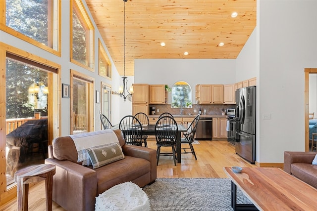 living room with plenty of natural light, light wood-type flooring, wood ceiling, and high vaulted ceiling