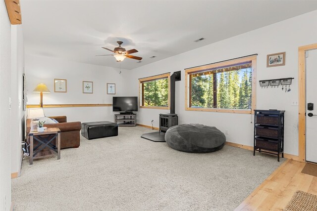 living room featuring a wood stove, ceiling fan, and hardwood / wood-style floors