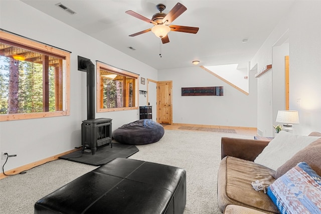 living room with ceiling fan, a wood stove, and carpet floors