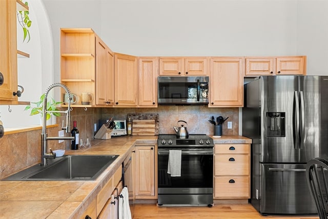 kitchen featuring decorative backsplash, appliances with stainless steel finishes, sink, light brown cabinets, and tile countertops