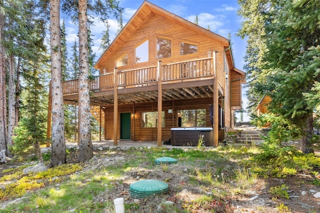 rear view of property with a wooden deck and a hot tub