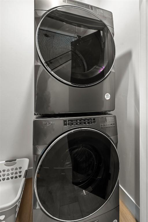 clothes washing area featuring stacked washing maching and dryer and hardwood / wood-style floors