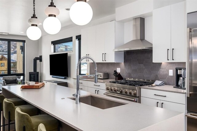 kitchen featuring white cabinets, tasteful backsplash, hanging light fixtures, and wall chimney exhaust hood