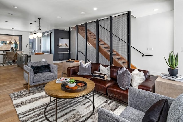 living room featuring an inviting chandelier, light hardwood / wood-style flooring, and sink