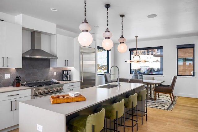 kitchen featuring sink, premium appliances, an island with sink, and wall chimney exhaust hood