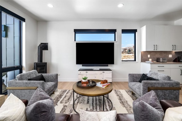 living room with light hardwood / wood-style floors and a wood stove