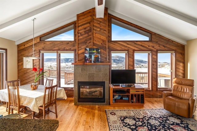 living room featuring hardwood / wood-style flooring, a fireplace, lofted ceiling with beams, and wood walls