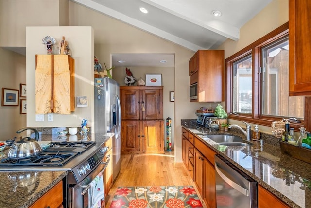 kitchen with stainless steel appliances, vaulted ceiling with beams, sink, and dark stone counters