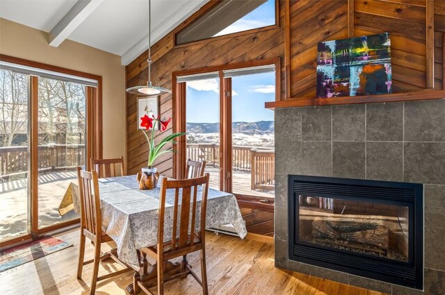 dining space featuring a multi sided fireplace, a mountain view, lofted ceiling with beams, and hardwood / wood-style floors