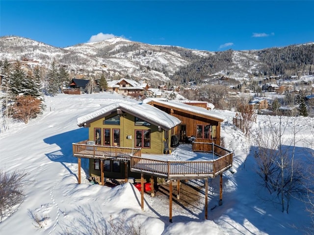 snow covered back of property featuring a deck with mountain view