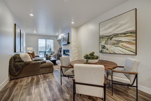 dining room featuring hardwood / wood-style flooring and a stone fireplace