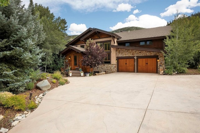 view of front of property with driveway, stone siding, and a garage