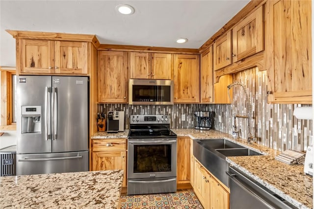 kitchen featuring backsplash, light stone counters, recessed lighting, appliances with stainless steel finishes, and a sink