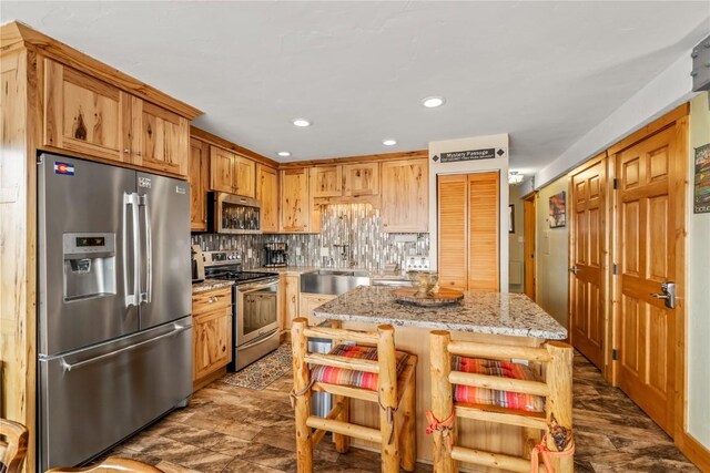 kitchen with light stone counters, backsplash, a center island, recessed lighting, and appliances with stainless steel finishes