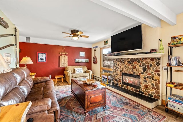 living area featuring beam ceiling, wood finished floors, a fireplace, a baseboard radiator, and ceiling fan