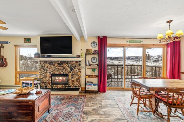 dining room with beam ceiling, a healthy amount of sunlight, a fireplace, and an inviting chandelier