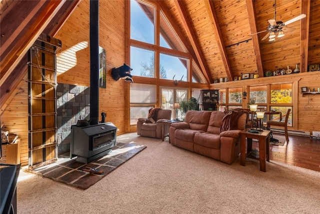 carpeted living room with wooden walls, beam ceiling, high vaulted ceiling, wooden ceiling, and a wood stove