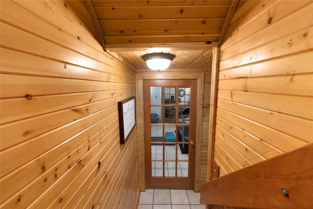 entryway with wood walls, light tile patterned flooring, wood ceiling, and vaulted ceiling