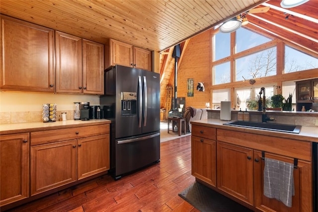 kitchen with sink, dark wood-type flooring, wooden ceiling, stainless steel fridge, and vaulted ceiling