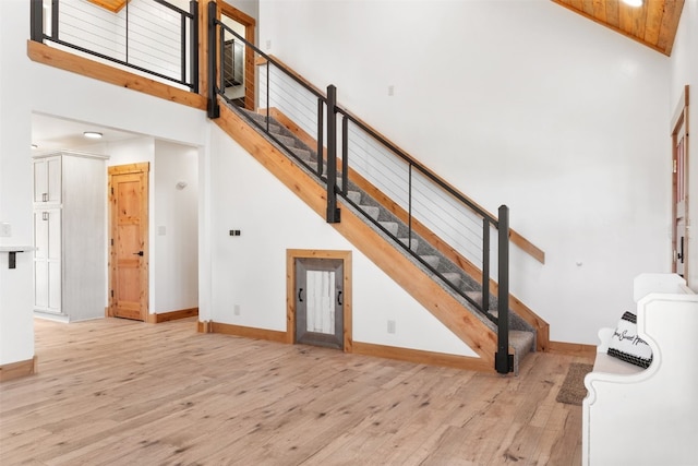 staircase with high vaulted ceiling and wood-type flooring