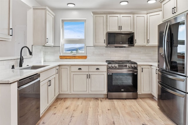 kitchen with decorative backsplash, sink, stainless steel appliances, and light hardwood / wood-style flooring