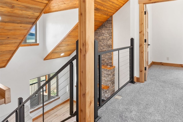 corridor featuring wooden ceiling, light carpet, and high vaulted ceiling