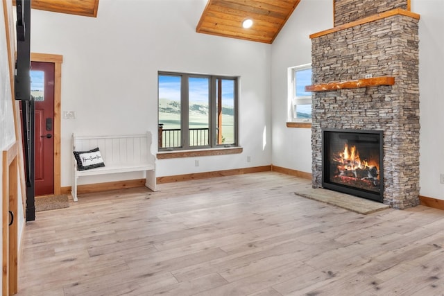 unfurnished living room featuring wooden ceiling, a fireplace, a towering ceiling, and light hardwood / wood-style flooring