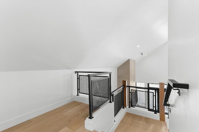 stairs with hardwood / wood-style floors and vaulted ceiling