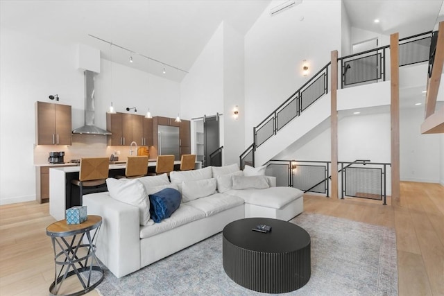 living room with light wood-type flooring and a towering ceiling