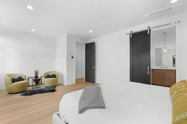 bedroom featuring hardwood / wood-style floors, a barn door, and sink