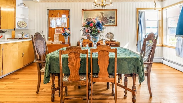 dining area with a notable chandelier, light wood-type flooring, and baseboard heating