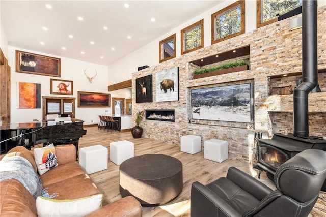 living room with a wood stove, a towering ceiling, and light wood-type flooring