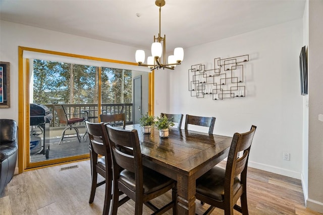 dining space featuring light wood-style floors, a chandelier, visible vents, and baseboards