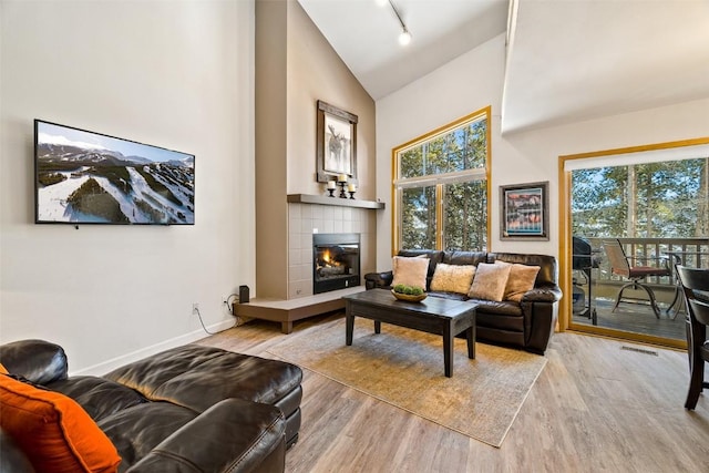 living room with plenty of natural light, a tiled fireplace, and wood finished floors