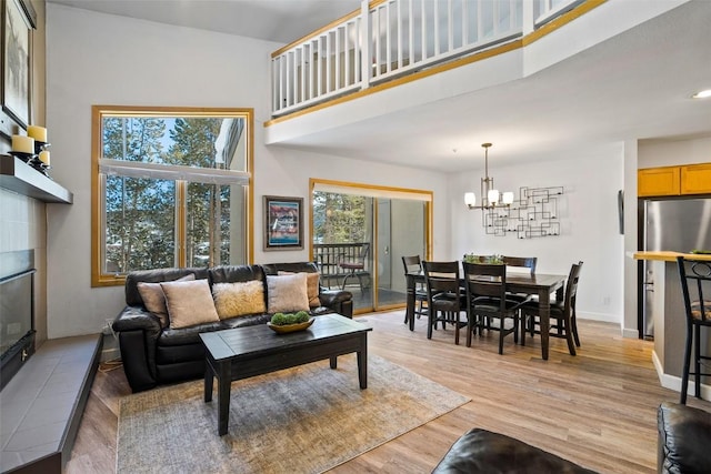 living area featuring a high ceiling, a fireplace, light wood-style flooring, and a healthy amount of sunlight