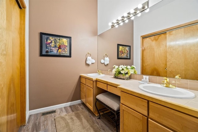 full bathroom featuring wood finished floors, visible vents, a sink, and double vanity