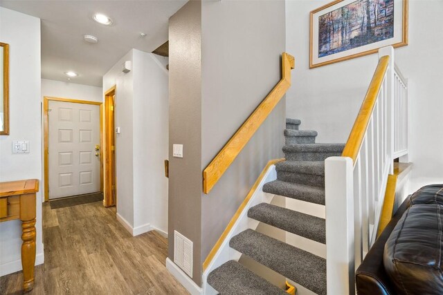 staircase featuring baseboards, visible vents, wood finished floors, and recessed lighting