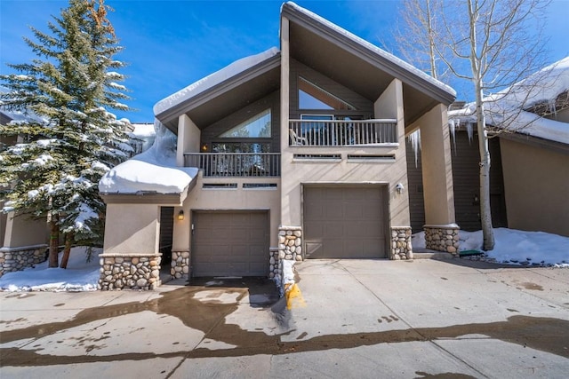 view of front of property with a balcony, stone siding, a garage, and stucco siding