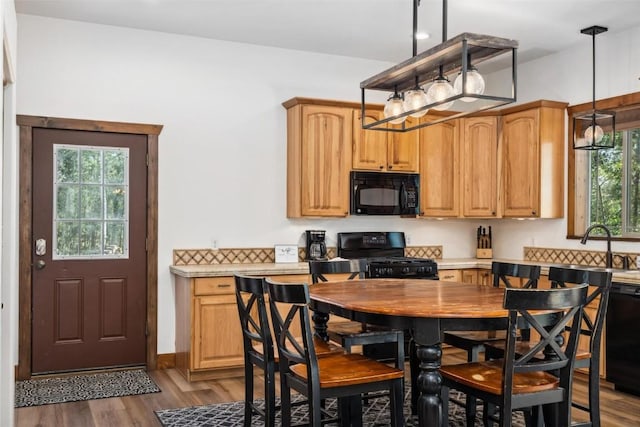 kitchen featuring black appliances, light wood-type flooring, hanging light fixtures, and a wealth of natural light