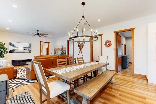 dining area with ceiling fan with notable chandelier and light hardwood / wood-style floors