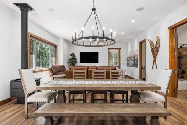 dining room featuring a wood stove, light hardwood / wood-style floors, and a notable chandelier