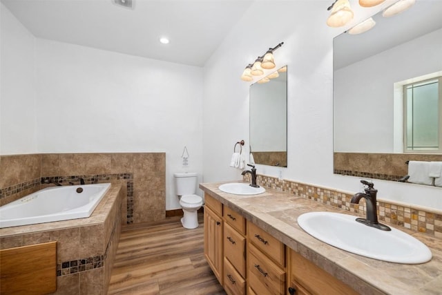 bathroom featuring hardwood / wood-style flooring, vanity, toilet, and tiled tub