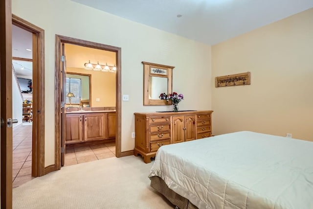 bedroom with connected bathroom, light carpet, and light tile patterned flooring